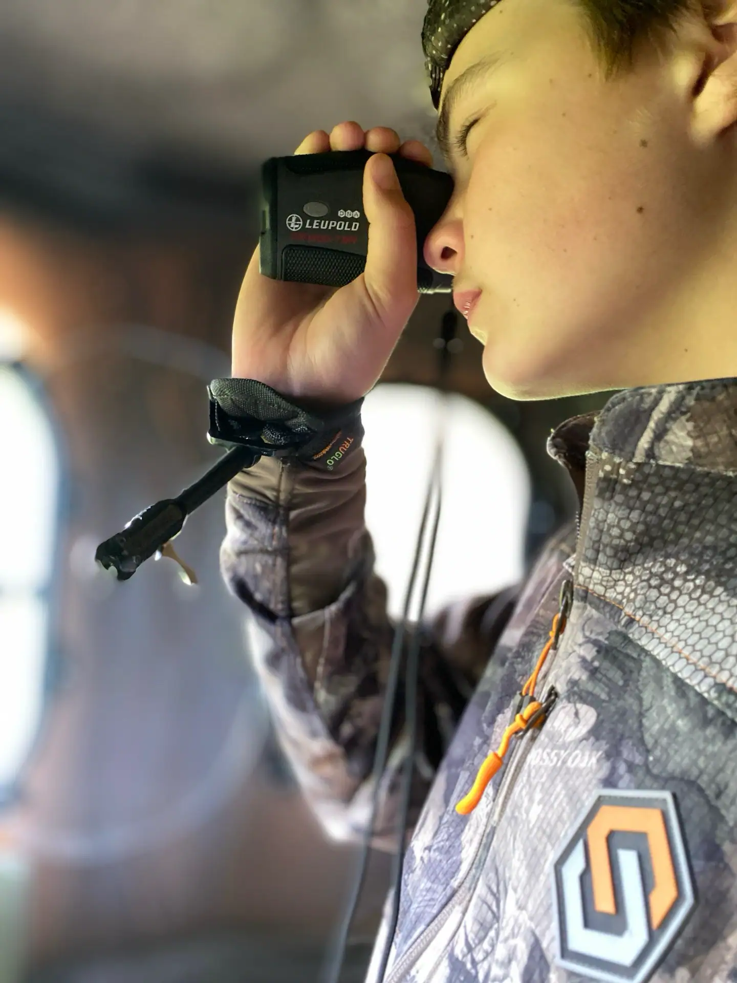 Teen looking through rangefinder inside a hunting blind
