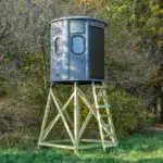 White Oak XT Blind in Fog Gray with gun windows and side door set by edge of woods