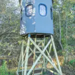 Alt corner view of Poplar Gun XT Blind on elevated stand in woods